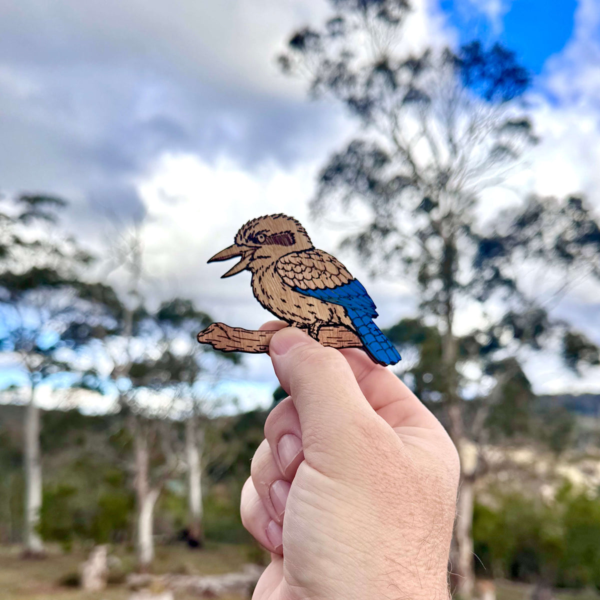 Hand holding onto a timber kookaburra magnet